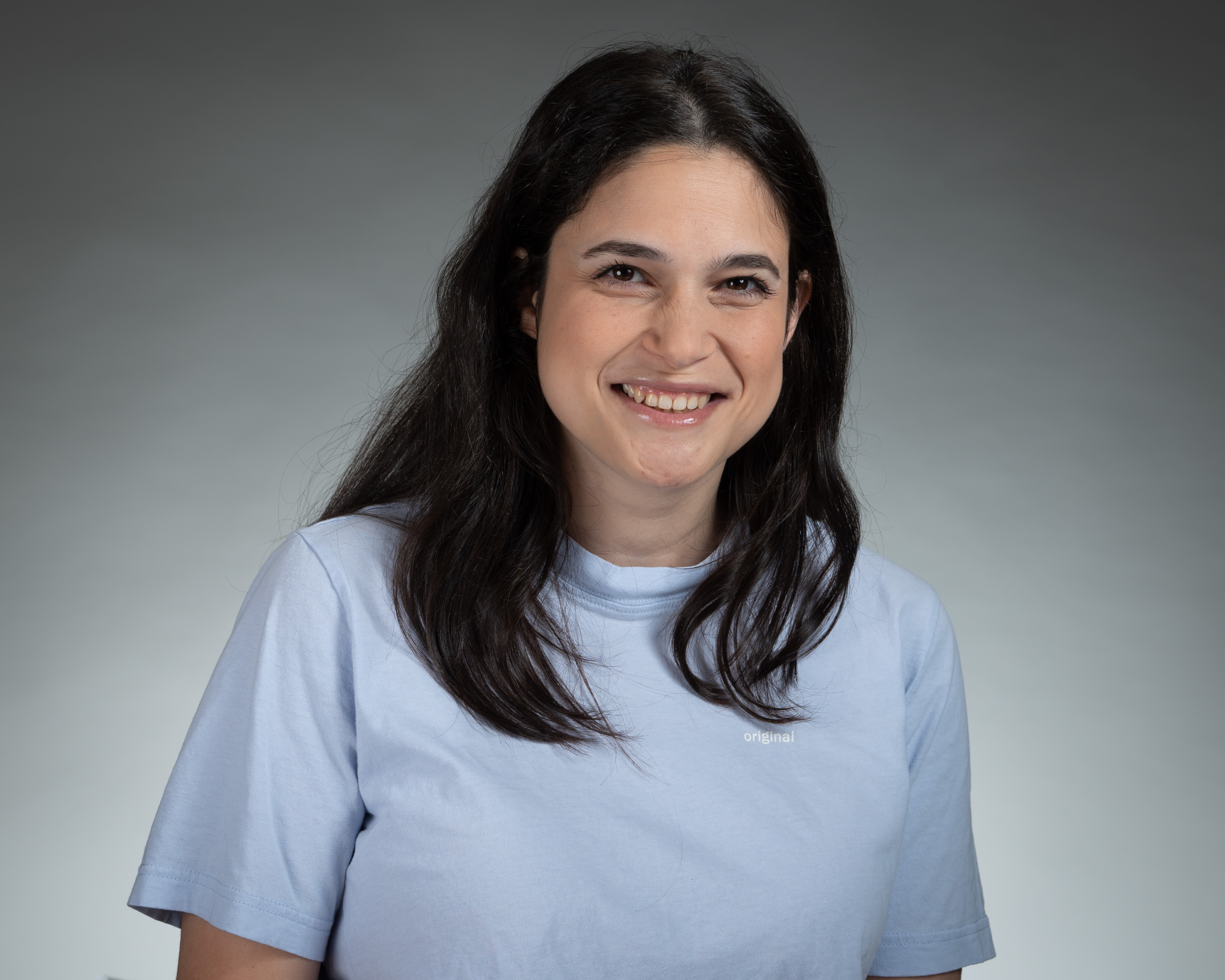 Portrait of a man with brown hair and glasses on a flat gray background.
